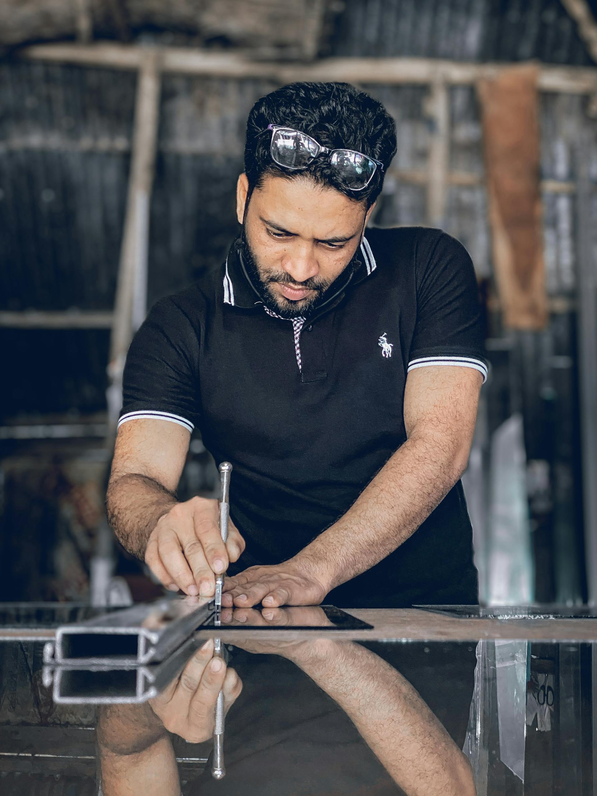 A skilled craftsman focusing on cutting glass in a workshop using precision tools.