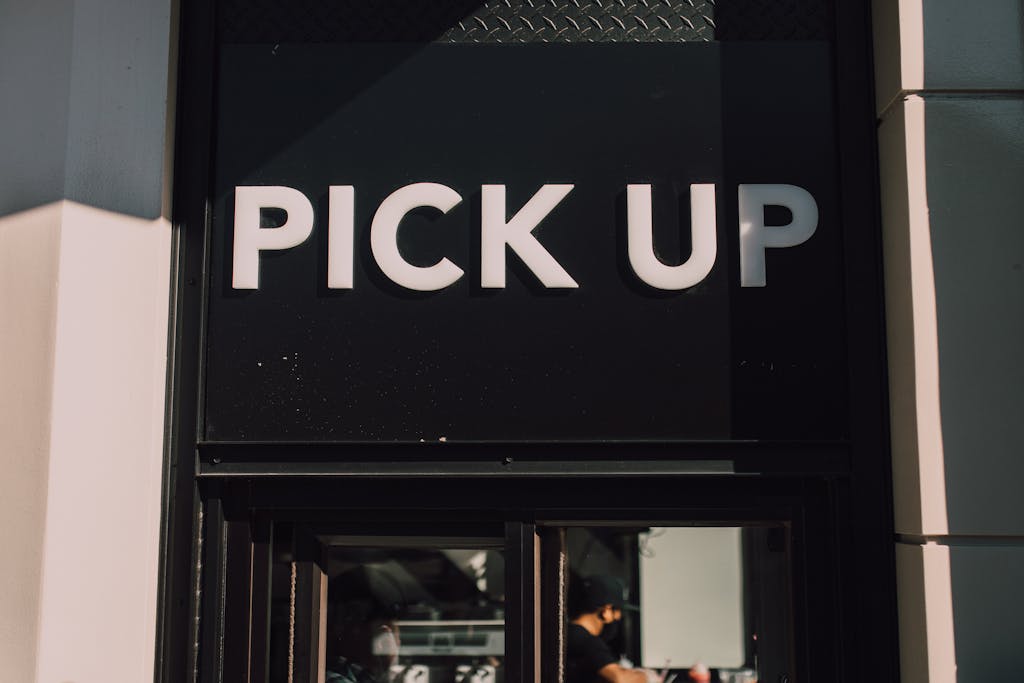 Exterior view of a restaurant pickup window with a sign reading 'Pick Up'.